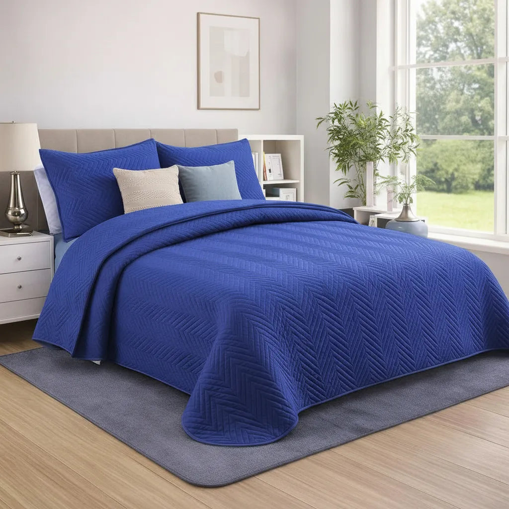 Blue quilted coverlet on a bed in a bedroom with a window and decor.