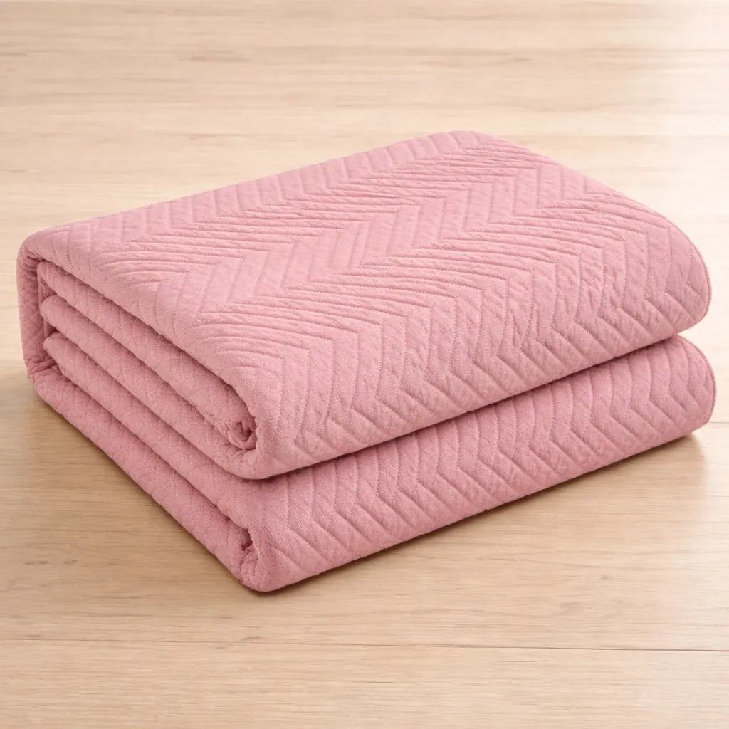 Folded pink quilt on a wooden surface