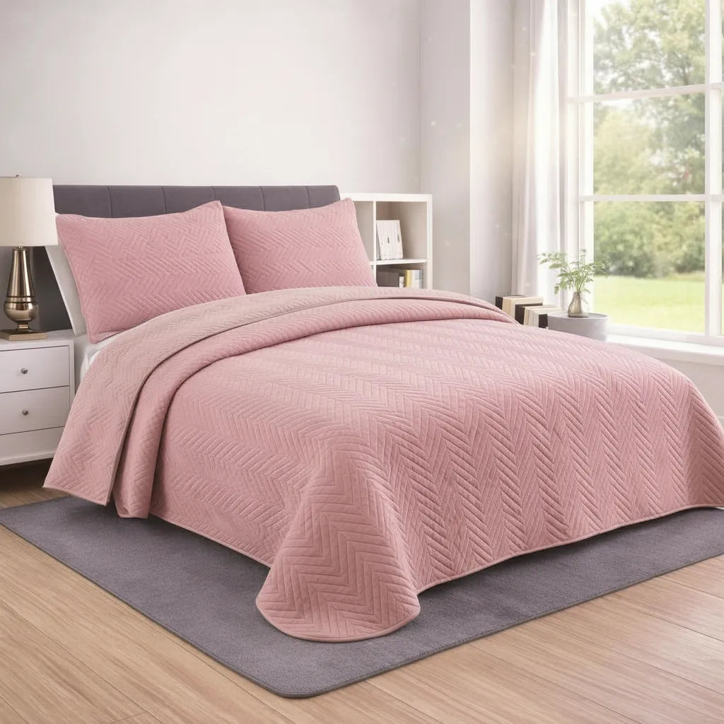 Pink quilt and pillow set on a bed in a bedroom with a window and lamp.